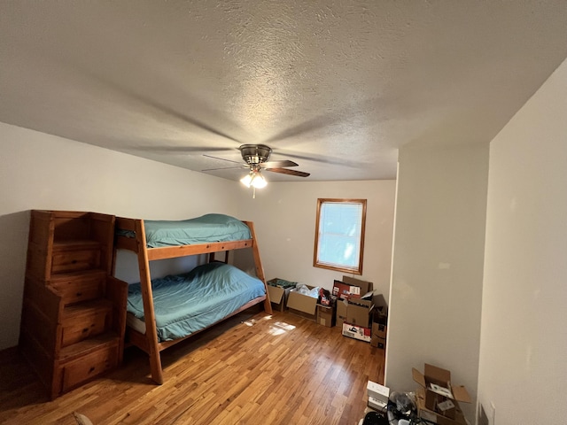 bedroom with a ceiling fan, a textured ceiling, and light wood-type flooring