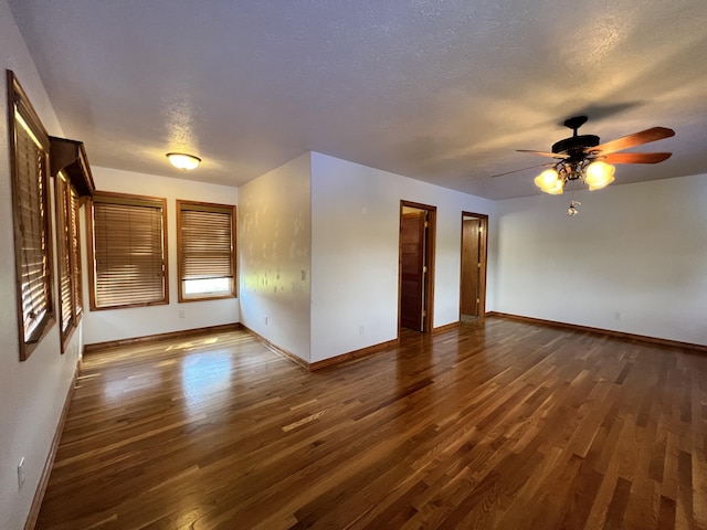 spare room featuring dark wood finished floors, a textured ceiling, baseboards, and ceiling fan