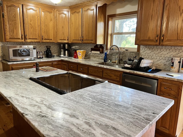 kitchen with brown cabinetry, stainless steel appliances, and a sink