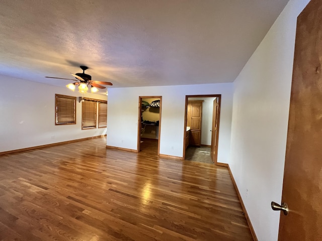 empty room with baseboards, a ceiling fan, and wood finished floors