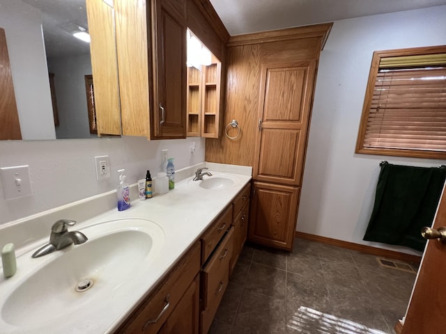 bathroom featuring baseboards, visible vents, a sink, and double vanity