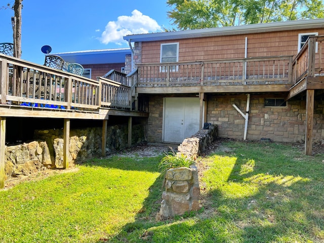 back of house featuring a lawn, stone siding, and a deck