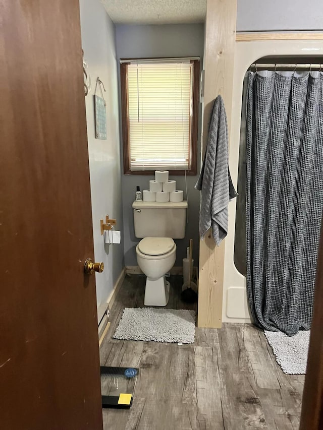 bathroom with walk in shower, hardwood / wood-style floors, a textured ceiling, and toilet