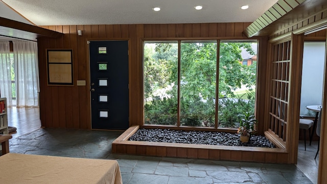 entryway with a textured ceiling and wooden walls