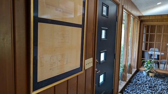 entryway featuring wood walls and a textured ceiling