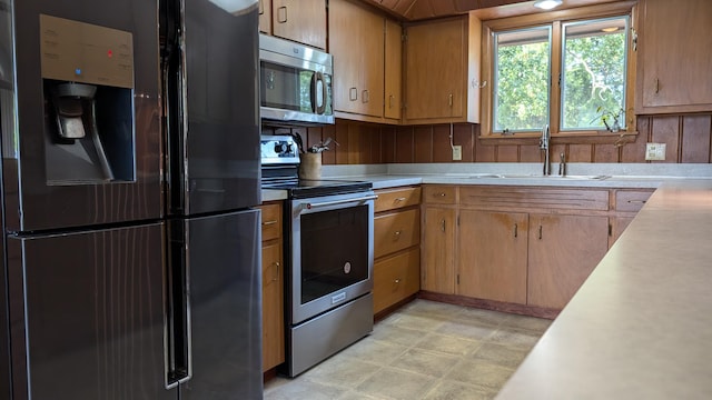 kitchen featuring wooden walls, stainless steel appliances, and sink