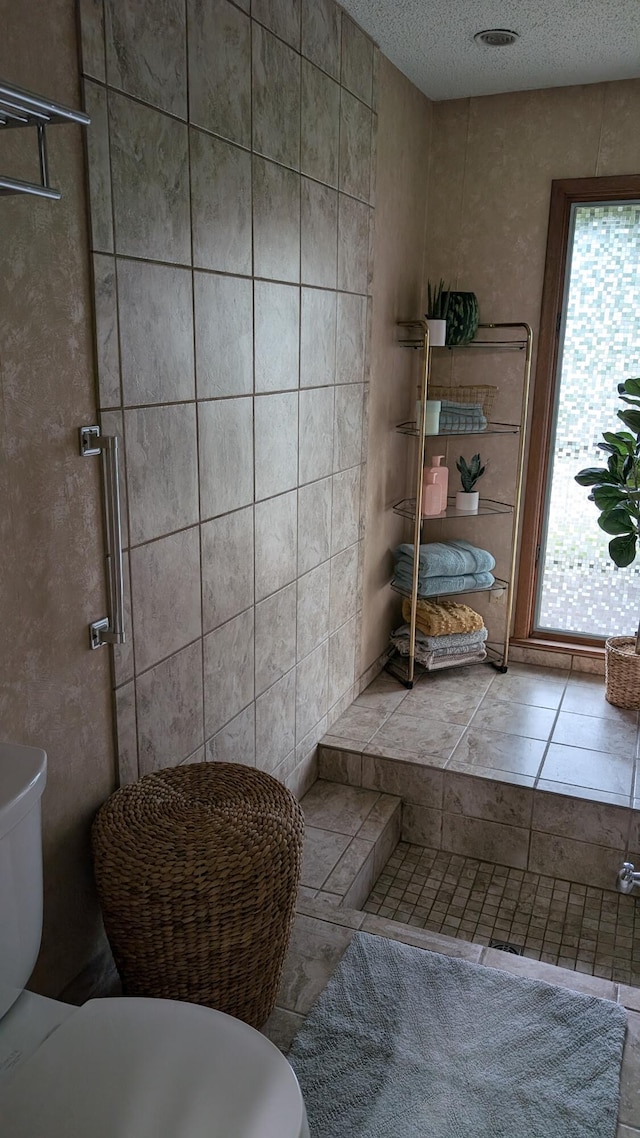 bathroom with an enclosed shower, toilet, and a textured ceiling