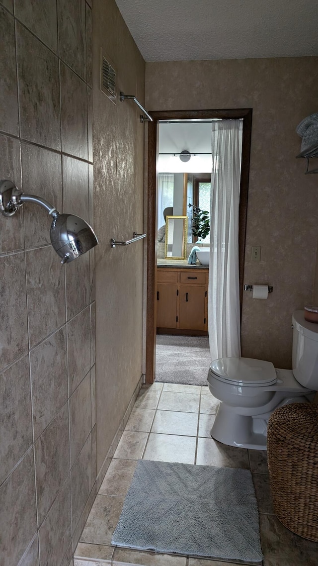 bathroom featuring a textured ceiling, tile patterned flooring, toilet, and curtained shower