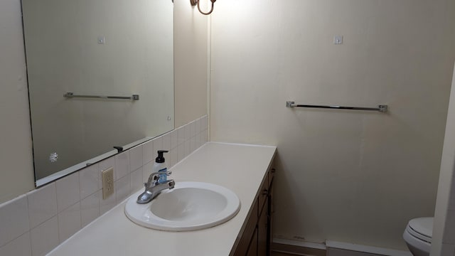 bathroom featuring tasteful backsplash, vanity, and toilet