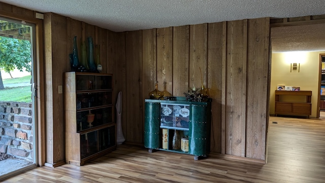 bar with hardwood / wood-style floors, wooden walls, and a textured ceiling