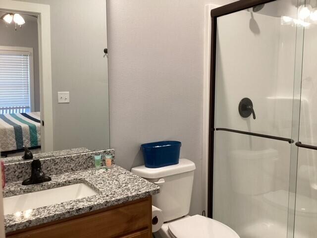 bathroom featuring an enclosed shower, vanity, and toilet