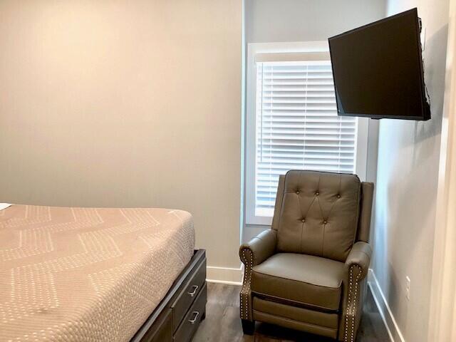 bedroom with dark hardwood / wood-style floors and multiple windows