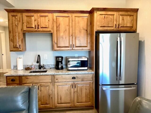 kitchen with stainless steel appliances, sink, and light stone counters