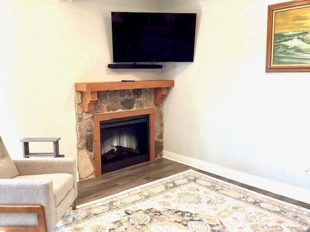 unfurnished room featuring a stone fireplace and hardwood / wood-style floors