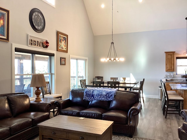 living room with wood-type flooring, high vaulted ceiling, and a chandelier