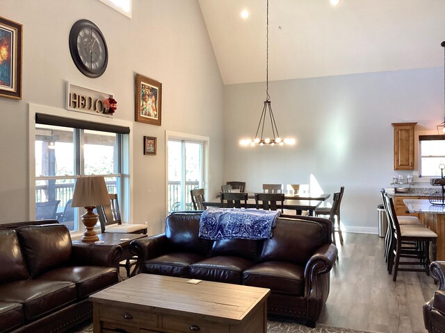 living room featuring hardwood / wood-style flooring, a notable chandelier, and high vaulted ceiling