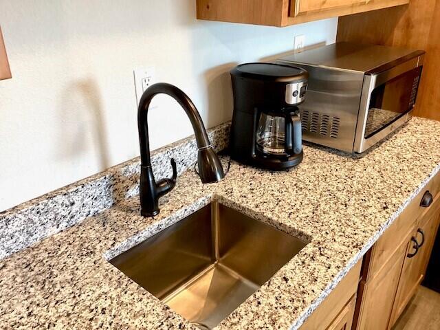 interior details featuring light stone countertops and sink