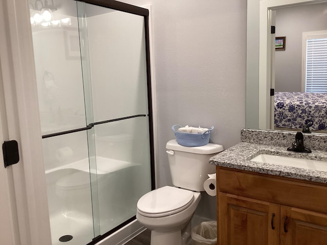 bathroom featuring a shower with shower door, vanity, and toilet