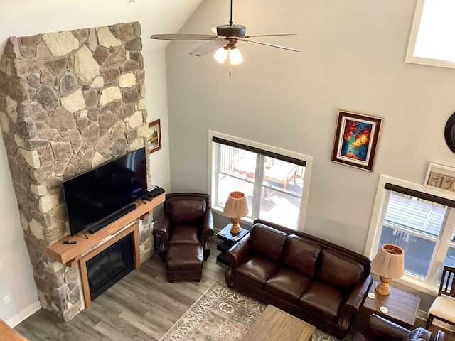 living room featuring a fireplace, wood-type flooring, high vaulted ceiling, and ceiling fan