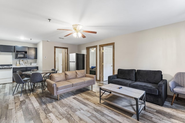 living room with hardwood / wood-style flooring, ceiling fan, and sink