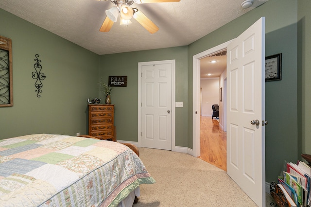 bedroom with ceiling fan, light carpet, and a textured ceiling