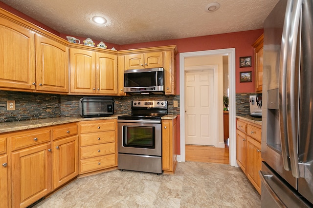 kitchen with light stone countertops, appliances with stainless steel finishes, a textured ceiling, and decorative backsplash