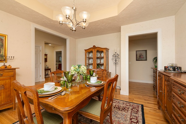 dining space with a chandelier, light hardwood / wood-style flooring, and a textured ceiling