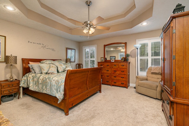 carpeted bedroom featuring a raised ceiling and ceiling fan