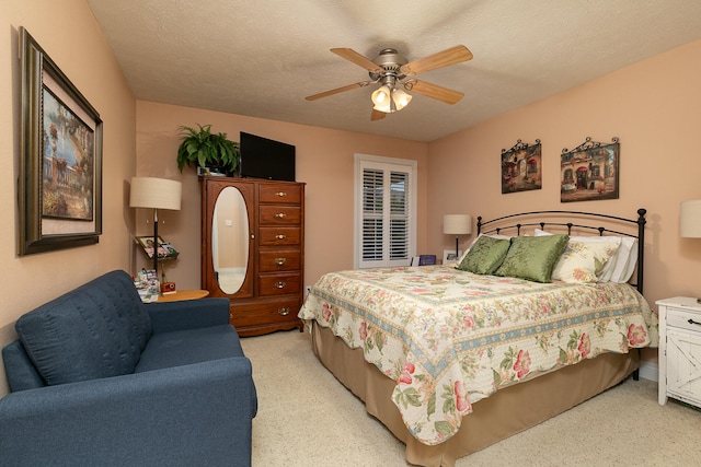 bedroom featuring ceiling fan, light colored carpet, and a textured ceiling