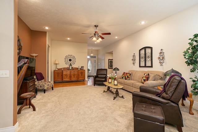 living room with a textured ceiling, ceiling fan, and carpet flooring