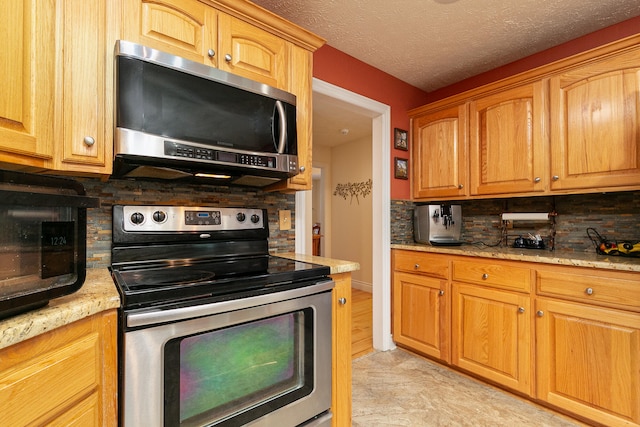 kitchen featuring light stone countertops, appliances with stainless steel finishes, backsplash, and a textured ceiling