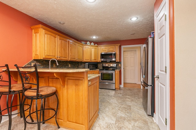 kitchen with sink, a kitchen breakfast bar, kitchen peninsula, stainless steel appliances, and decorative backsplash