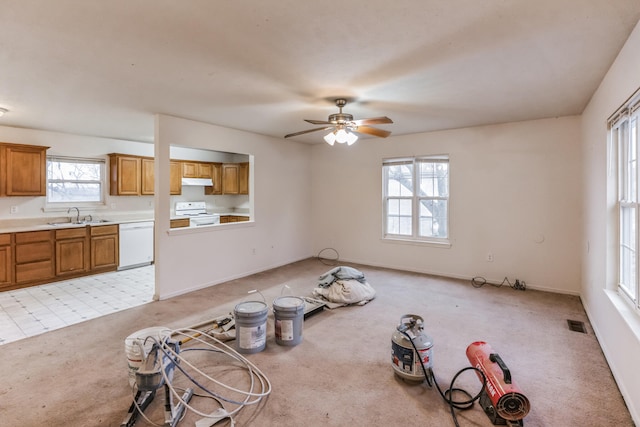 unfurnished dining area with plenty of natural light, light colored carpet, sink, and ceiling fan