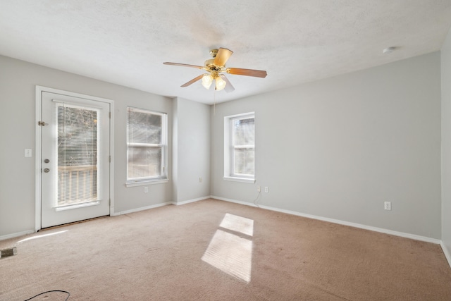 spare room with light colored carpet, a textured ceiling, and ceiling fan