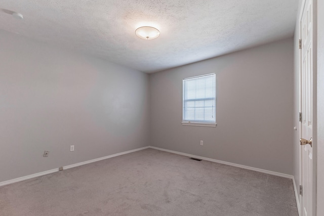 unfurnished room with a textured ceiling and light colored carpet