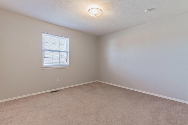 empty room with a textured ceiling and light carpet