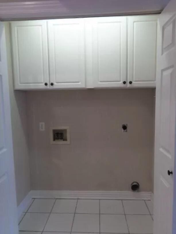 washroom featuring tile patterned floors, hookup for a washing machine, electric dryer hookup, cabinet space, and baseboards