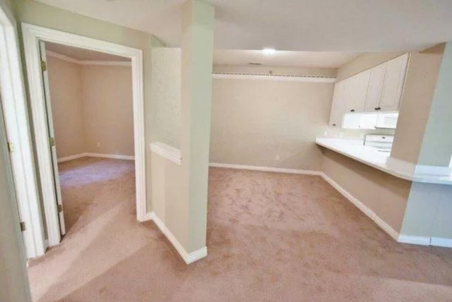 interior space with light countertops, white cabinetry, baseboards, and light carpet