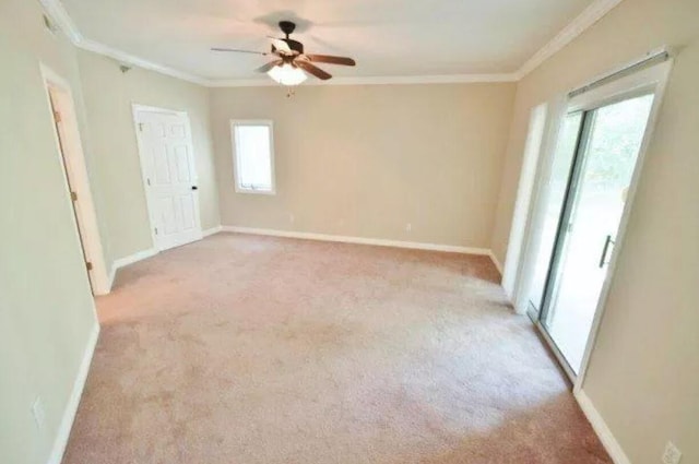 unfurnished room featuring light colored carpet, ceiling fan, baseboards, and crown molding