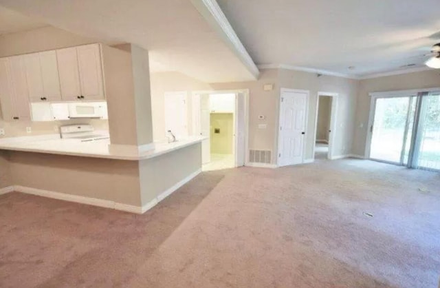 kitchen featuring white microwave, baseboards, range, and light carpet