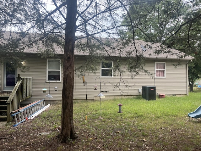 back of property featuring central air condition unit and a lawn