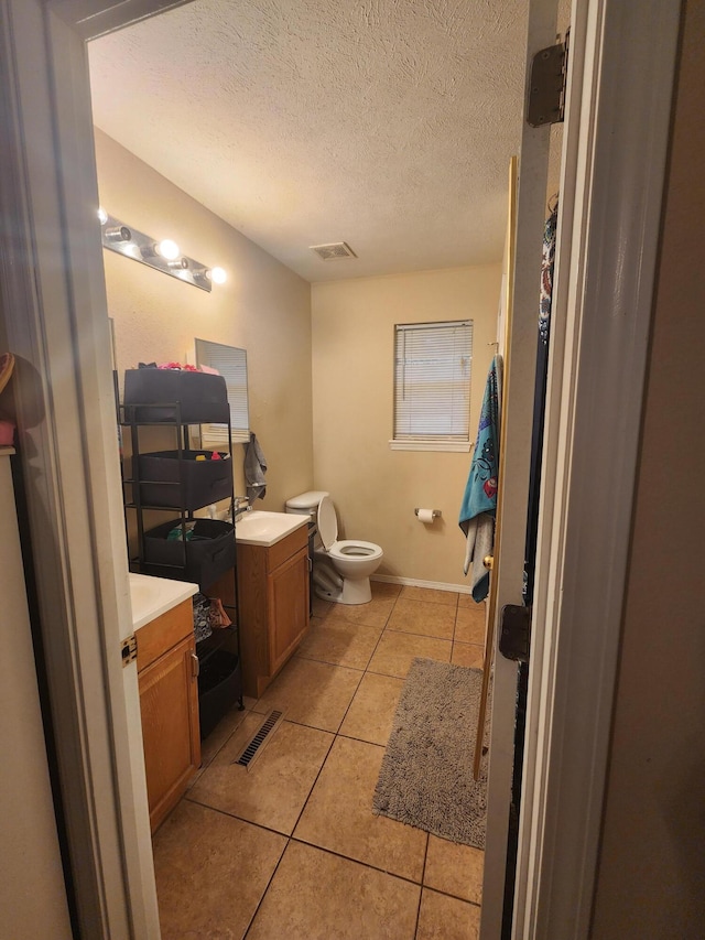 bathroom with a textured ceiling, tile patterned floors, vanity, and toilet