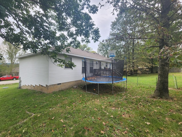 back of house with a trampoline and a lawn