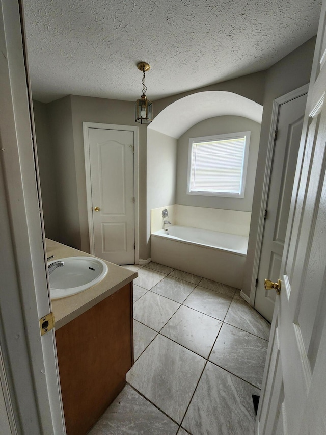 1213 Woodland, Monett, MO 65708 - bathroom featuring tile patterned flooring, a garden tub, vanity, and a textured ceiling
