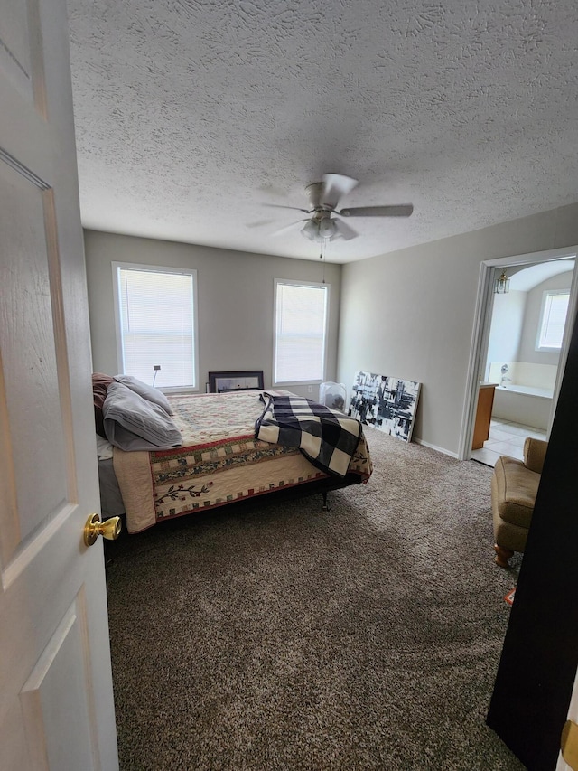 carpeted bedroom featuring ensuite bathroom, a textured ceiling, and ceiling fan