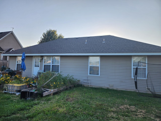1211 Woodland, Monett, MO 65708 - back of house with a lawn, a shingled roof, and a vegetable garden