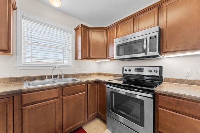 kitchen with light tile patterned floors, a textured ceiling, appliances with stainless steel finishes, and sink