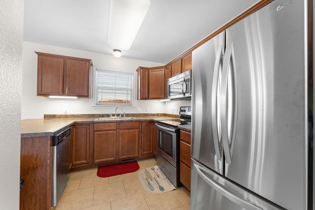 kitchen with appliances with stainless steel finishes, sink, and light tile patterned floors