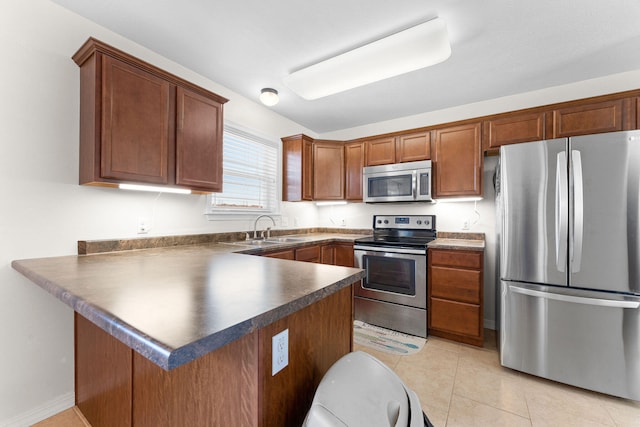 kitchen featuring light tile patterned floors, appliances with stainless steel finishes, sink, and kitchen peninsula