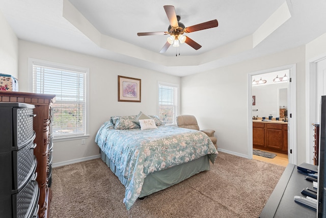 carpeted bedroom featuring ensuite bathroom, ceiling fan, and a raised ceiling